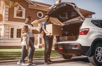 Family loading boxes into SUV outside home